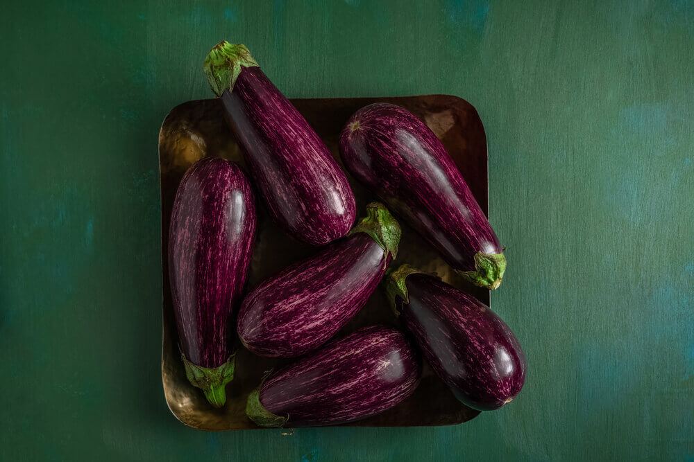 A plate of raw bright purple eggplant veggies